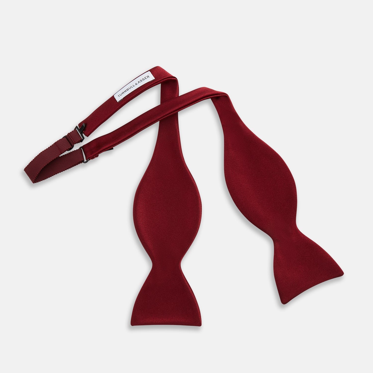 View 2 of product The Turnbull & Asser BURGUNDY SATIN BOW TIE features a deep red, smooth, and shiny finish—an essential accessory—neatly tied and showcased against a plain white background.