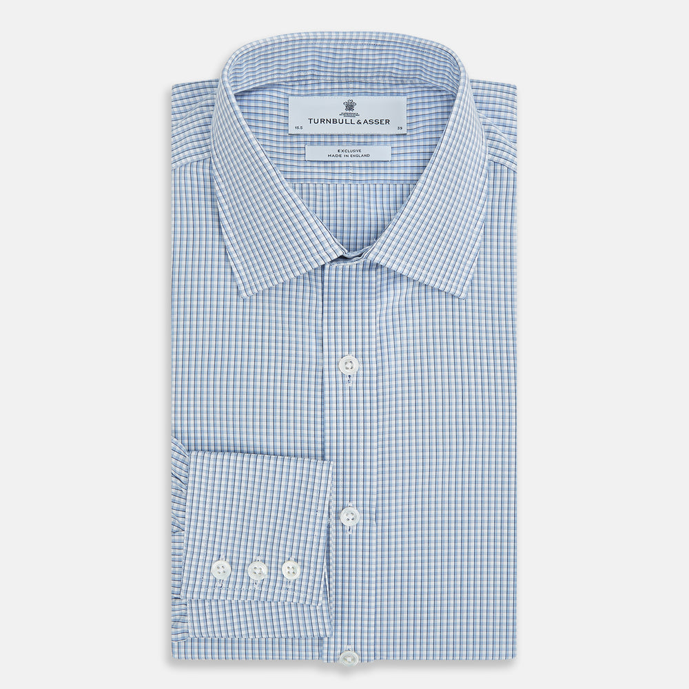 The Turnbull & Asser Blue Micro Shadow Check Mayfair Shirt features a long-sleeve, button-up design with a small blue and white check pattern, pointed T&A collar, and classic cuffs.