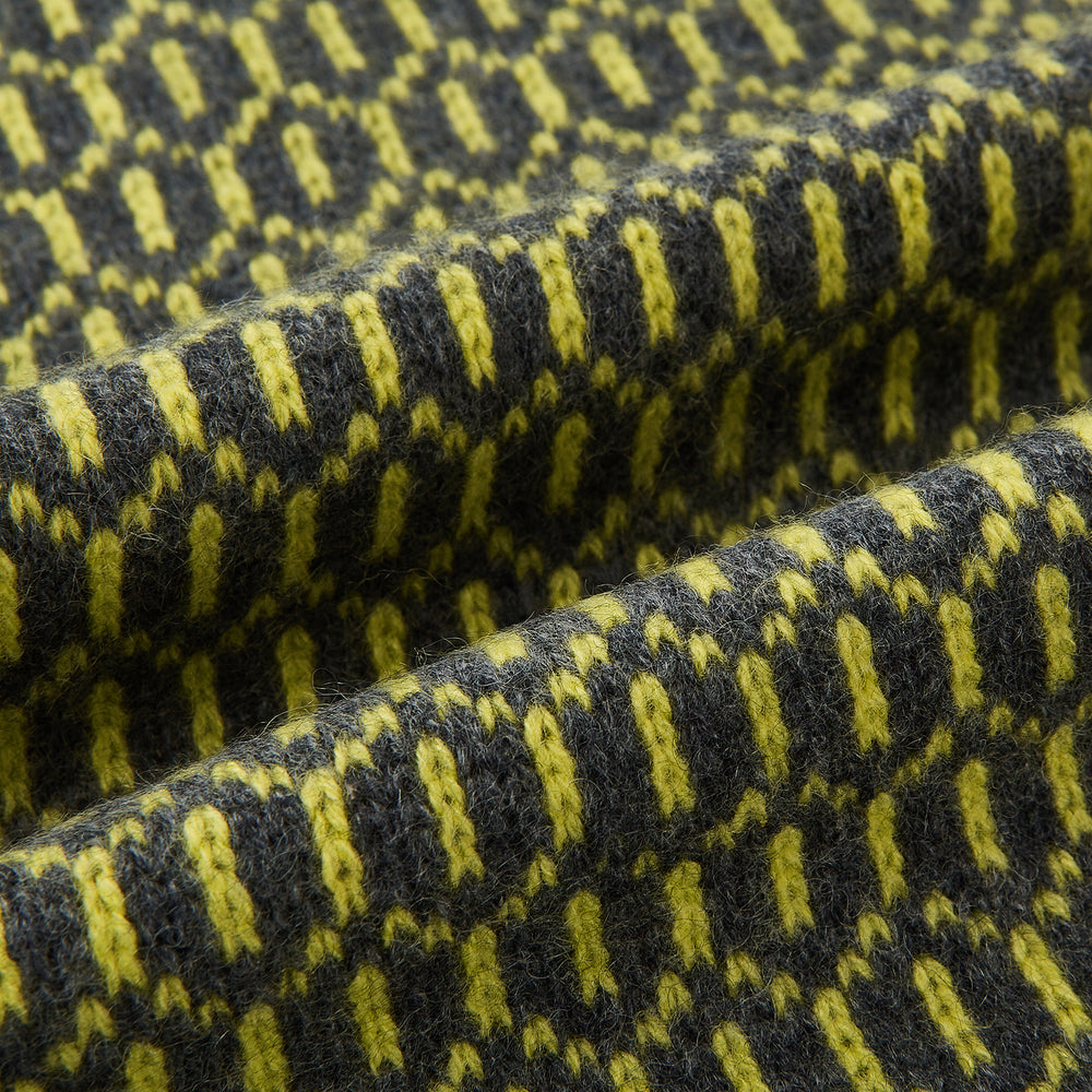 The Turnbull & Asser Graphite and Chartreuse Lemon Hexagon Cashmere Knitted Scarf features a geometric pattern in green and yellow tones, neatly folded to show both ends—an essential accessory with luxurious softness.