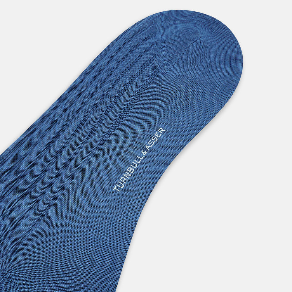 A single Azzurro Long Sock by Turnbull & Asser, in blue mercerised Egyptian cotton with a ribbed texture, is shown upright and angled left against a plain light background.