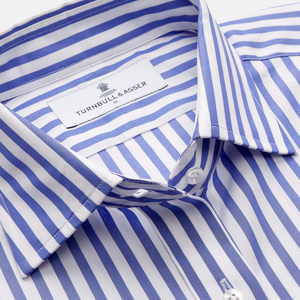 The Turnbull & Asser Pale Blue Candy Stripe Cotton Marlene Shirt is an oversized women's collared shirt with long sleeves, buttoned cuffs, and vertical blue and white stripes, shown laid flat on a white background.