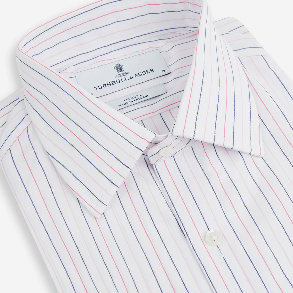 The Turnbull & Asser Pink and Blue Wide Pinstripe Mayfair Shirt features long sleeves, T&A collar, button-down front, and buttoned cuffs. It has bold pink and blue pinstripes on white and is laid flat on a white surface.