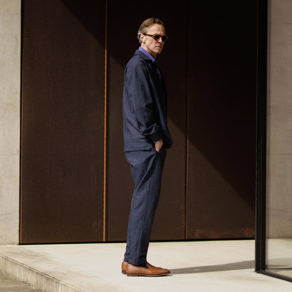 The Navy Tailored Pinstriped Shirt Jacket by Turnbull & Asser is a smart-casual, lightweight cotton-linen piece with long sleeves, a collar, left chest pocket, and front buttons for easy style.