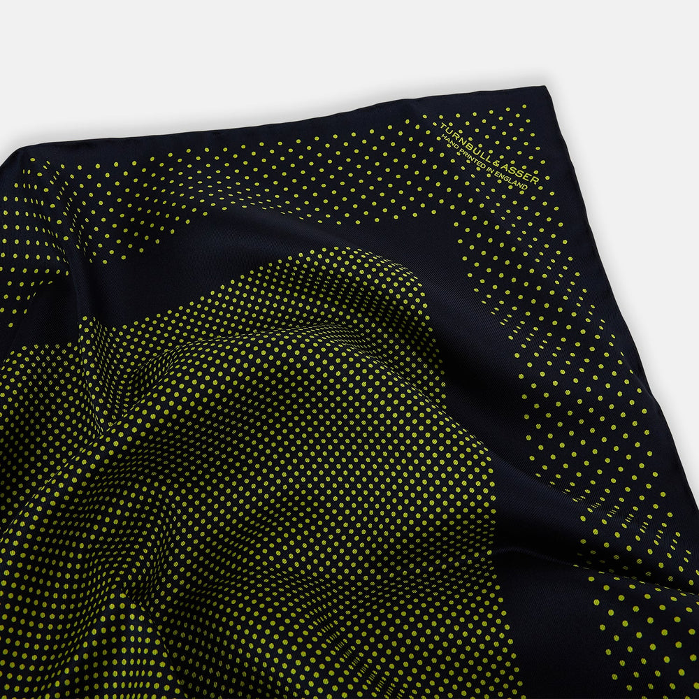 The Turnbull & Asser Navy and Yellow Dot Silk Pocket Square features a navy base with yellow dots, a solid navy border, and a folded corner showing the patterned underside for an elegant accent.