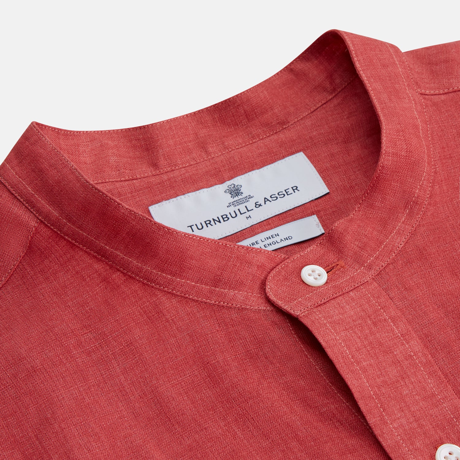 View 2 of product The Turnbull & Asser Plain Red Linen Weekend Fit Shirt with Stand Collar features long sleeves, a button-up front, and two buttoned-flap chest pockets. It is shown neatly laid flat on a plain light background.