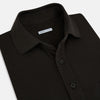 View 2 of product A brown cotton jersey polo shirt by Turnbull & Asser with short sleeves, a collar, three buttons, and a buttoned chest pocket, laid flat on a white background.