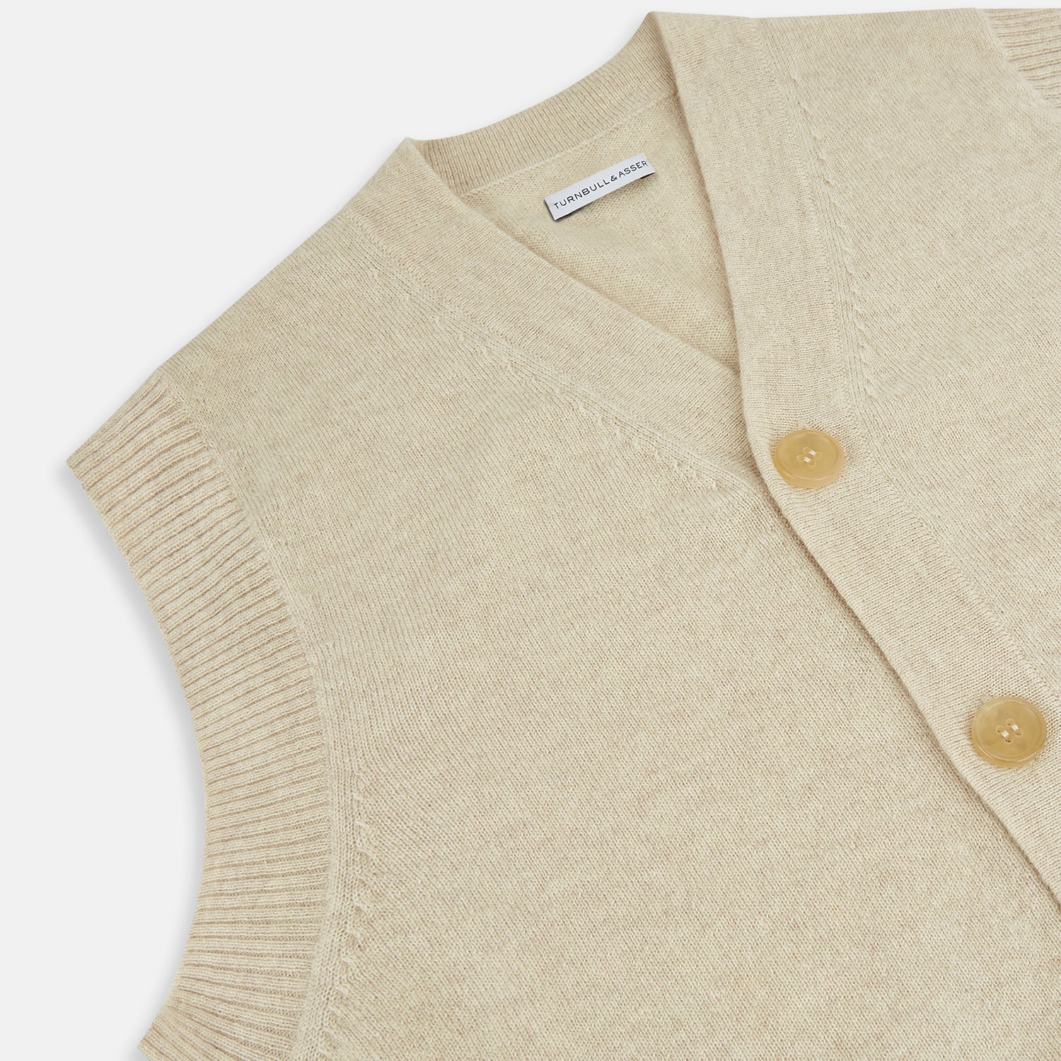 View 2 of product Turnbull & Asser’s Ivory Cashmere Sleeveless Cardigan features a button-down front, two small pockets, and ribbed trim at the hem, armholes, and collar—ideal for elegant looks. Shown on a white background.