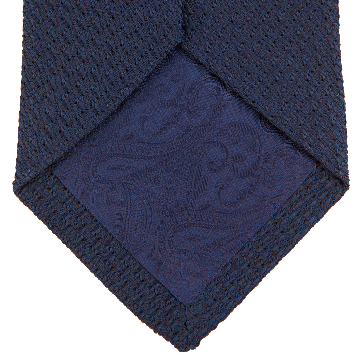View 4 of product The Turnbull & Asser Navy Plain Woven Grenadine Silk Tie, an essential accessory, is rolled at one end and displayed on a plain white background.
