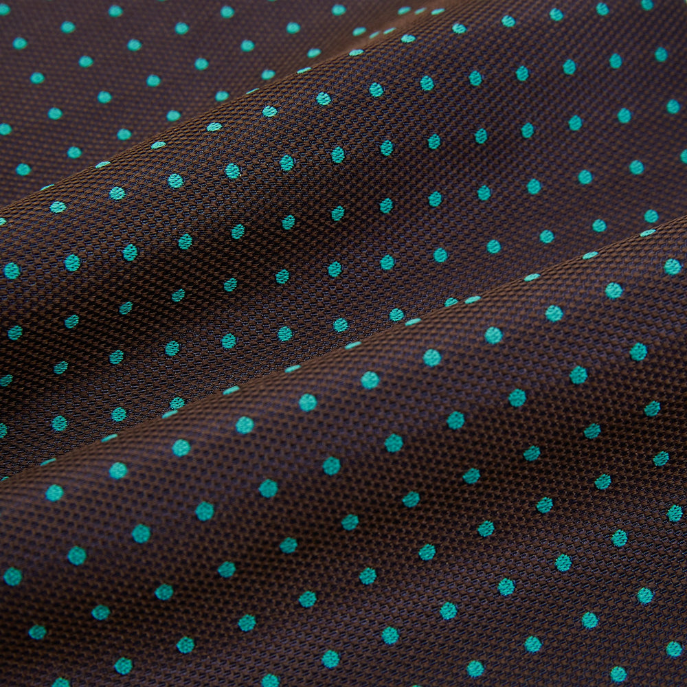 The Turnbull & Asser Blue and Dark Brown Micro Dot Silk Cravat features evenly spaced blue micro dots on dark brown silk, displayed neatly folded on a white background.