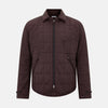 View 1 of product The Battersea Burgundy Quilted Jacket by Turnbull & Asser is a men's elegant outerwear featuring a front zipper, zippered side pockets, chest pocket, pointed collar, and buttoned cuffs, shown on a plain white background.