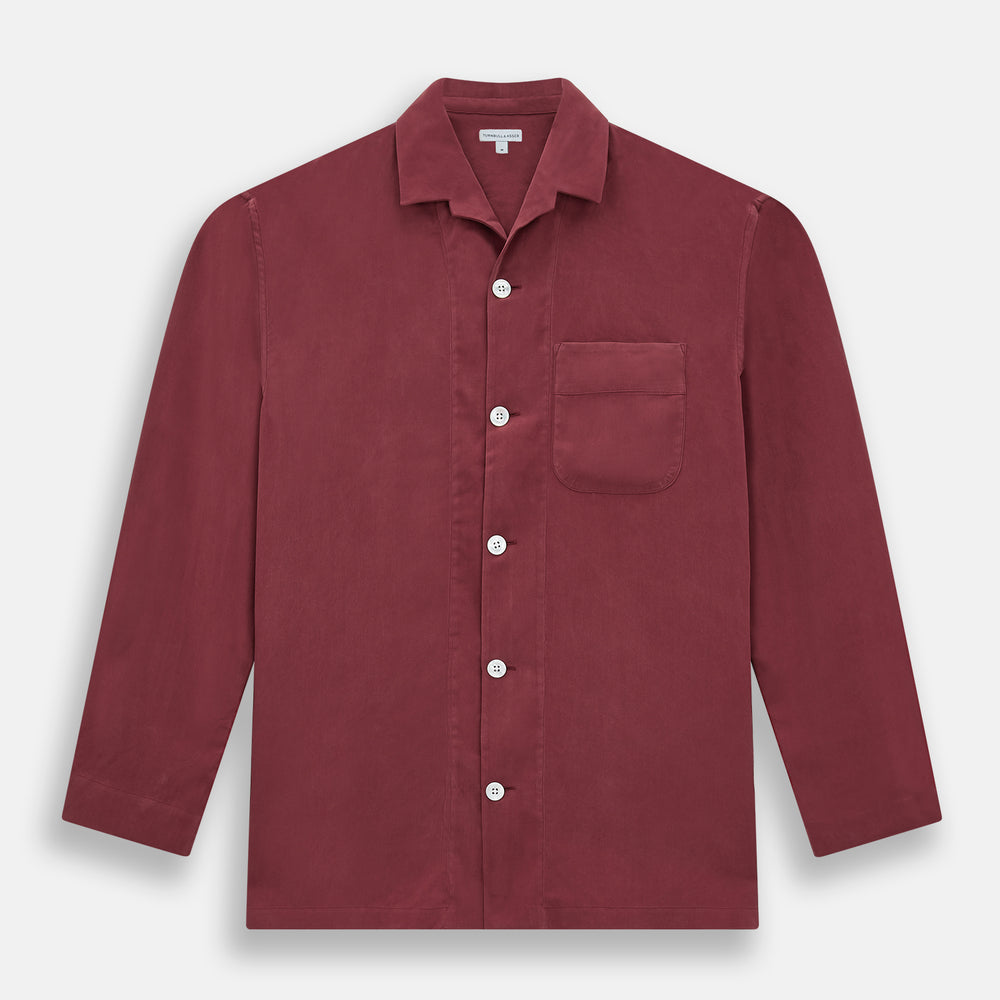 The Turnbull & Asser Burgundy Silk Pyjama Set features a long-sleeve, button-up shirt with chest pocket and matching pants with elastic waistband and side pocket, shown on a white background.