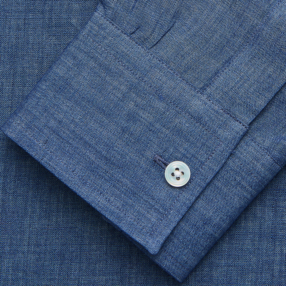 The Blue Weekend Fit Linen Finch Shirt by Turnbull & Asser features a Derby collar, chest pocket, and white buttons. Made from mid-blue linen chambray, it offers effortless casual style when laid flat on a plain white background.