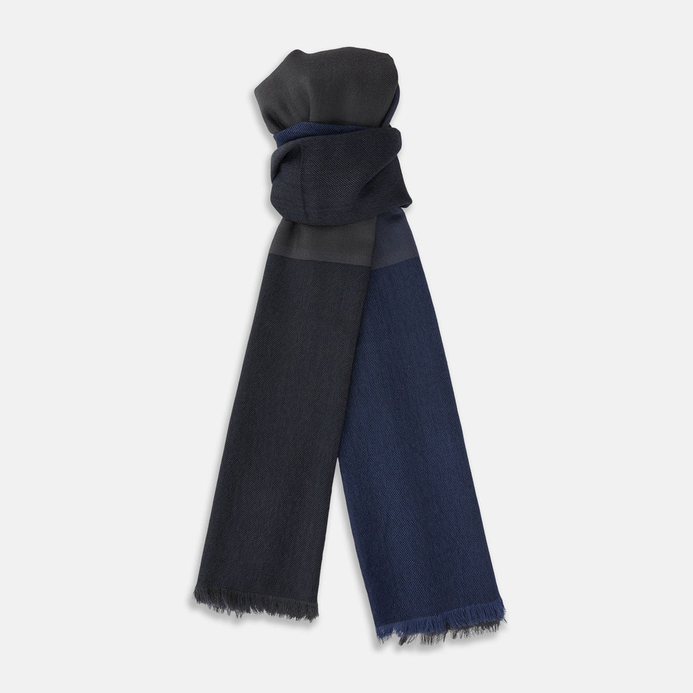 The Charcoal and Navy Cashmere Scarf by Turnbull & Asser features a color block design in dark hues, raw fringed edges, and a soft, smooth texture, elegantly displayed against a white background.