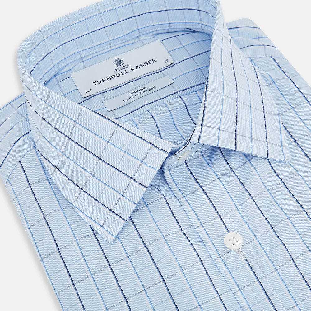 The Navy and Blue Combination Check Mayfair Shirt by Turnbull & Asser features a light blue base with a grid of thin dark blue lines, long sleeves, a pointed collar, and is neatly displayed on a plain white background.