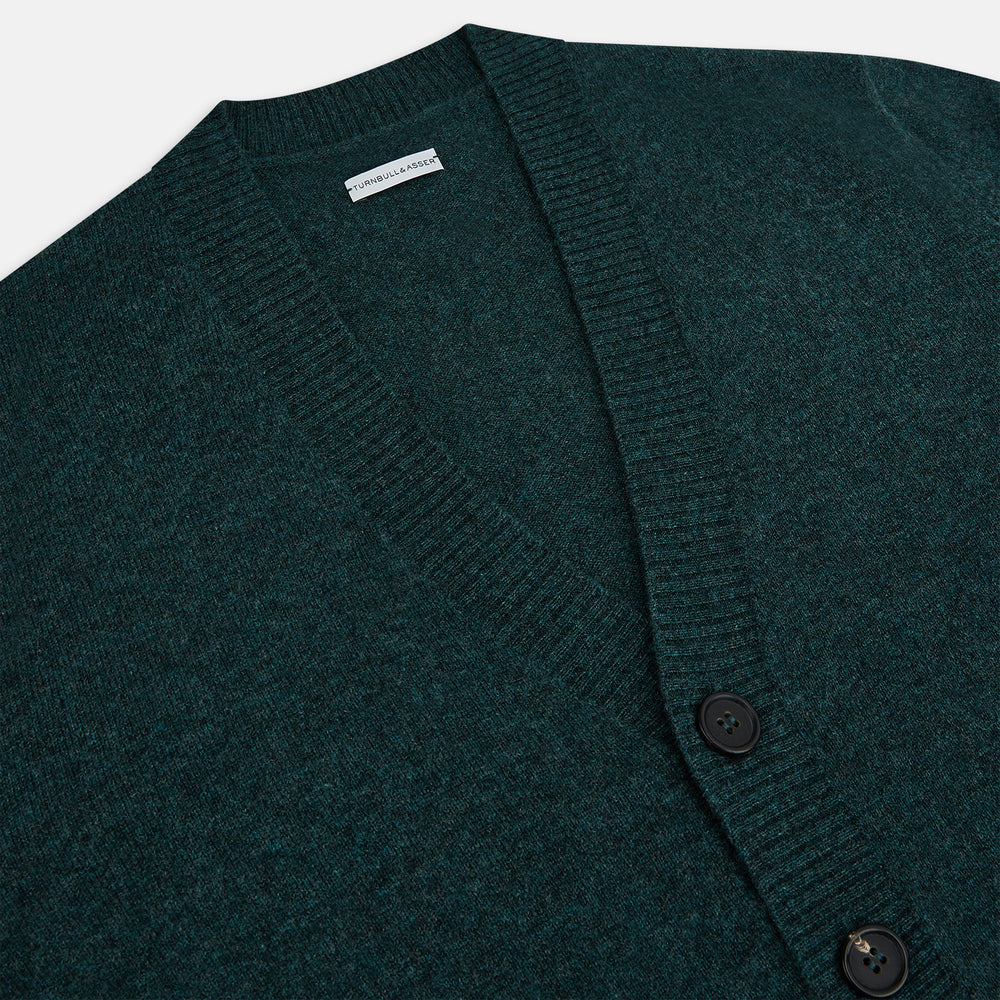 Turnbull & Asser’s Green Melange Cashmere Cardigan features a V-neck, long sleeves, ribbed cuffs and hem, two front pockets, and a button-up front—an essential knitwear piece shown against a white background.