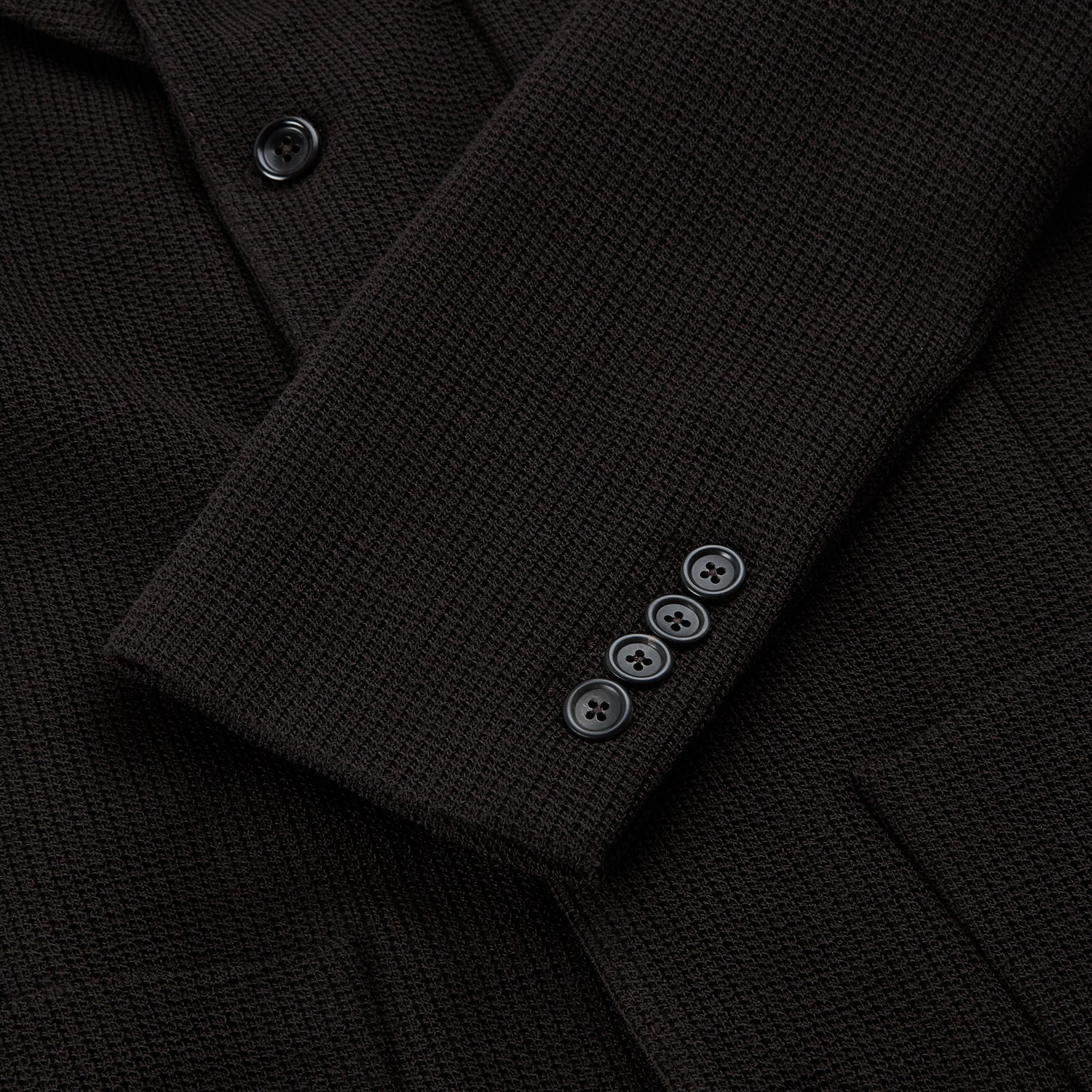 View 4 of product The Turnbull & Asser Dark Chocolate Knitted Cambridge Blazer for men, made from fine Italian wool with British tailoring, features a notched lapel, three front buttons, and three patch pockets, shown on a plain white background.