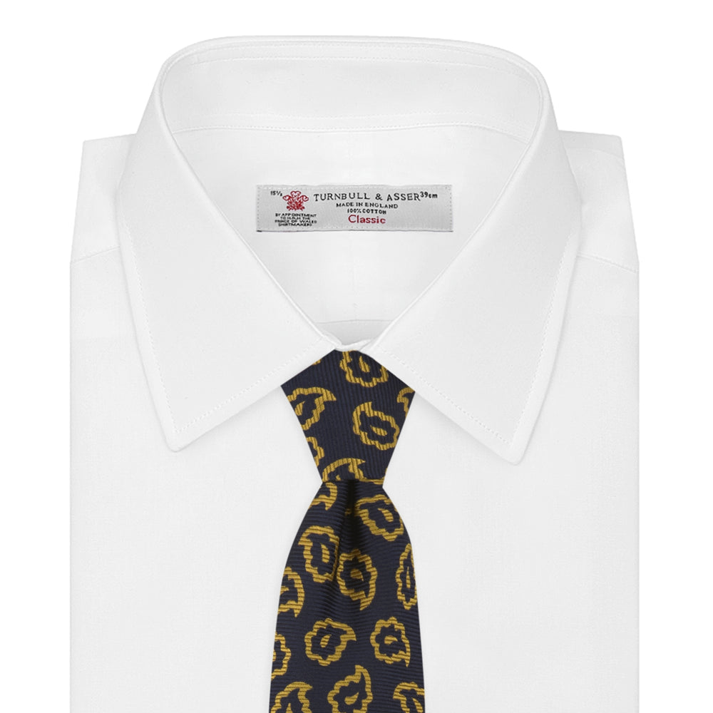 The Navy and Gold Petal Paisley Silk Tie by Turnbull & Asser features a repeating yellow abstract pattern, neatly rolled on a white background.
