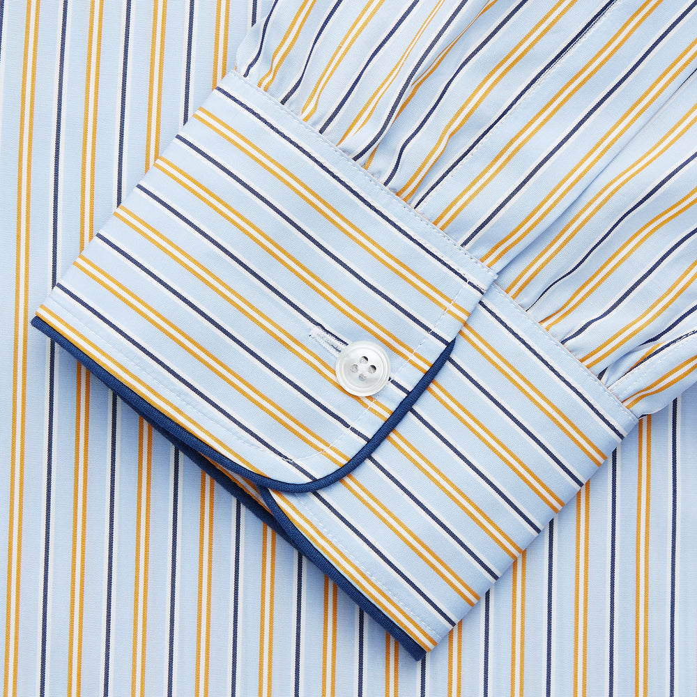 The Turnbull & Asser Blue, Orange and Navy Stripe Nightshirt is a loose-fitting shirt dress with vertical stripes, a pointed collar, chest pocket with blue trim, button-down front, long sleeves with cuffs, and a curved hem.