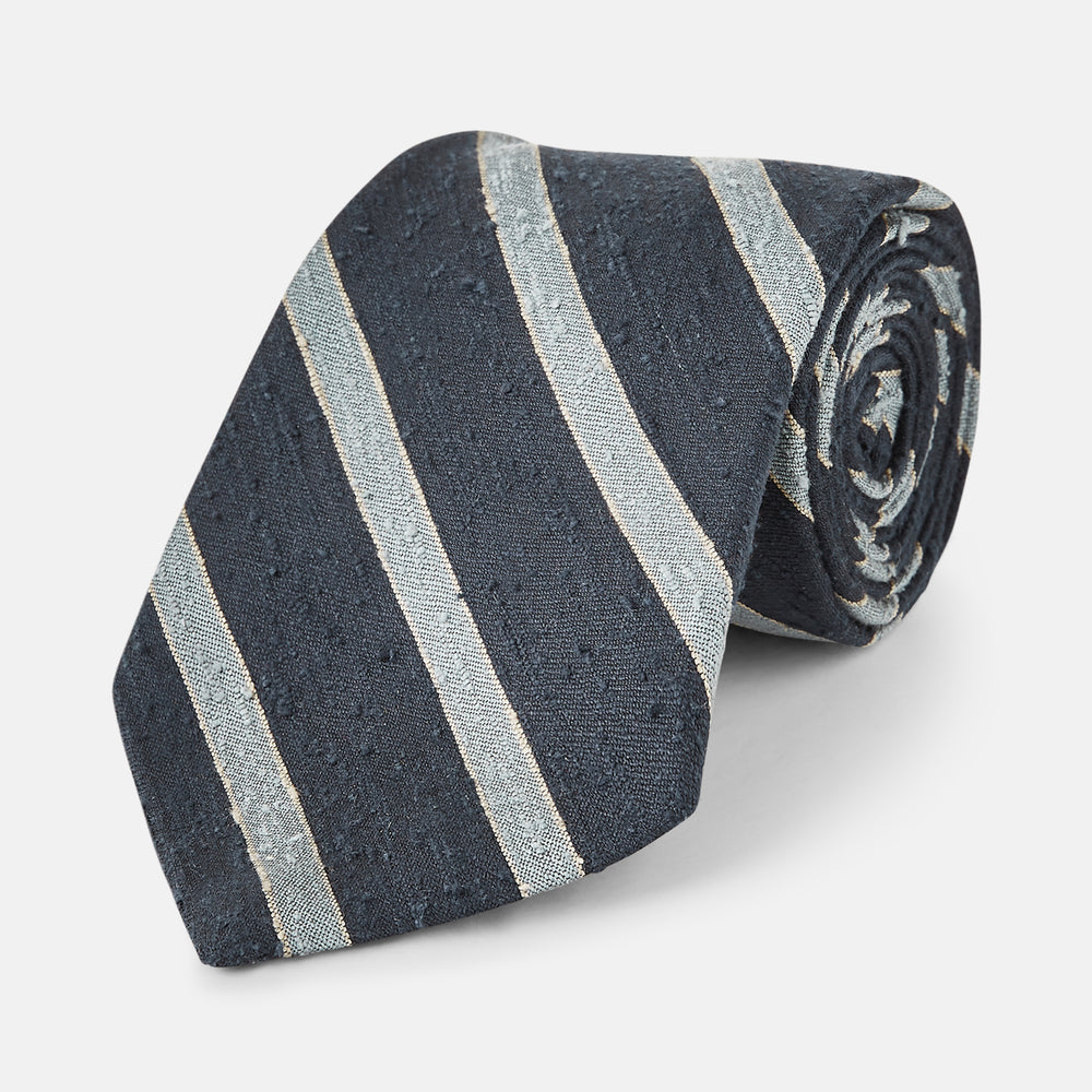 The Turnbull & Asser Blue & Silver Stripe Silk Tie, featuring wide diagonal stripes, is rolled up and displayed against a plain white background.