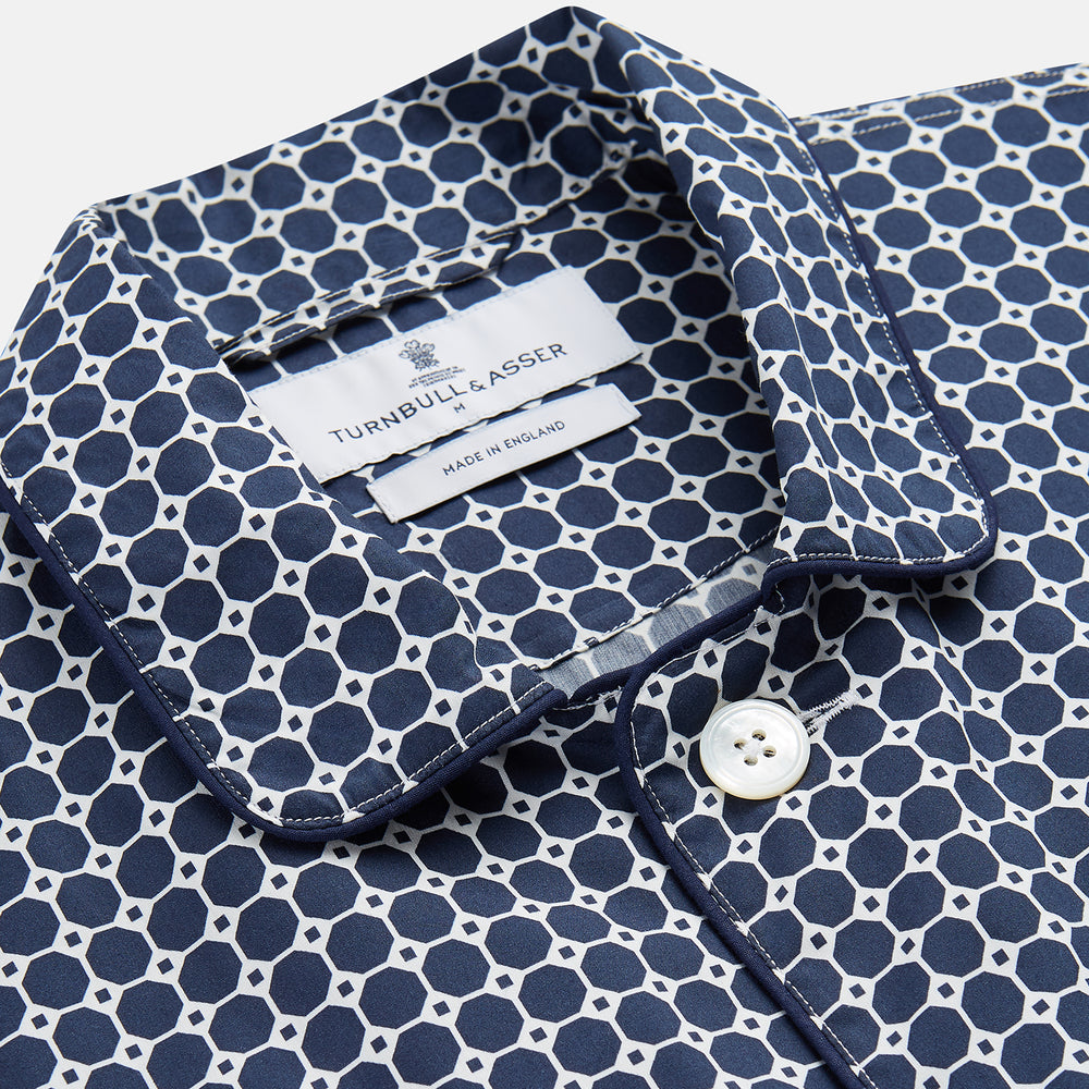 The Navy Motif Silk-Blend Hyde Pyjama Set by Turnbull & Asser features a blue and white pattern, long-sleeve button-up top with collar and front pocket, and matching pants, all displayed against a white background.