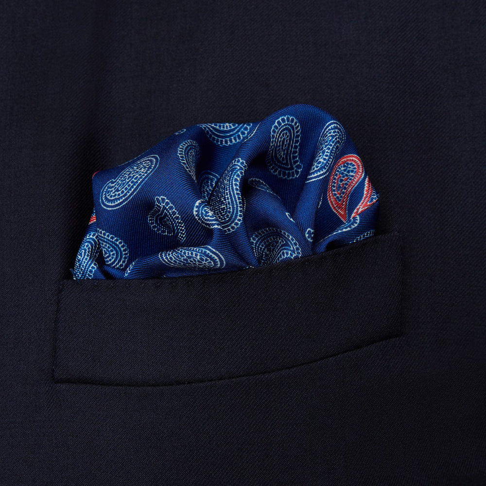 The Navy Multi Valentines Day Special Silk Pocket Square from Turnbull & Asser features a blue base with white and pink paisley motifs, a decorative border, and a discreet logo—an elegant gift for Valentine’s Day.