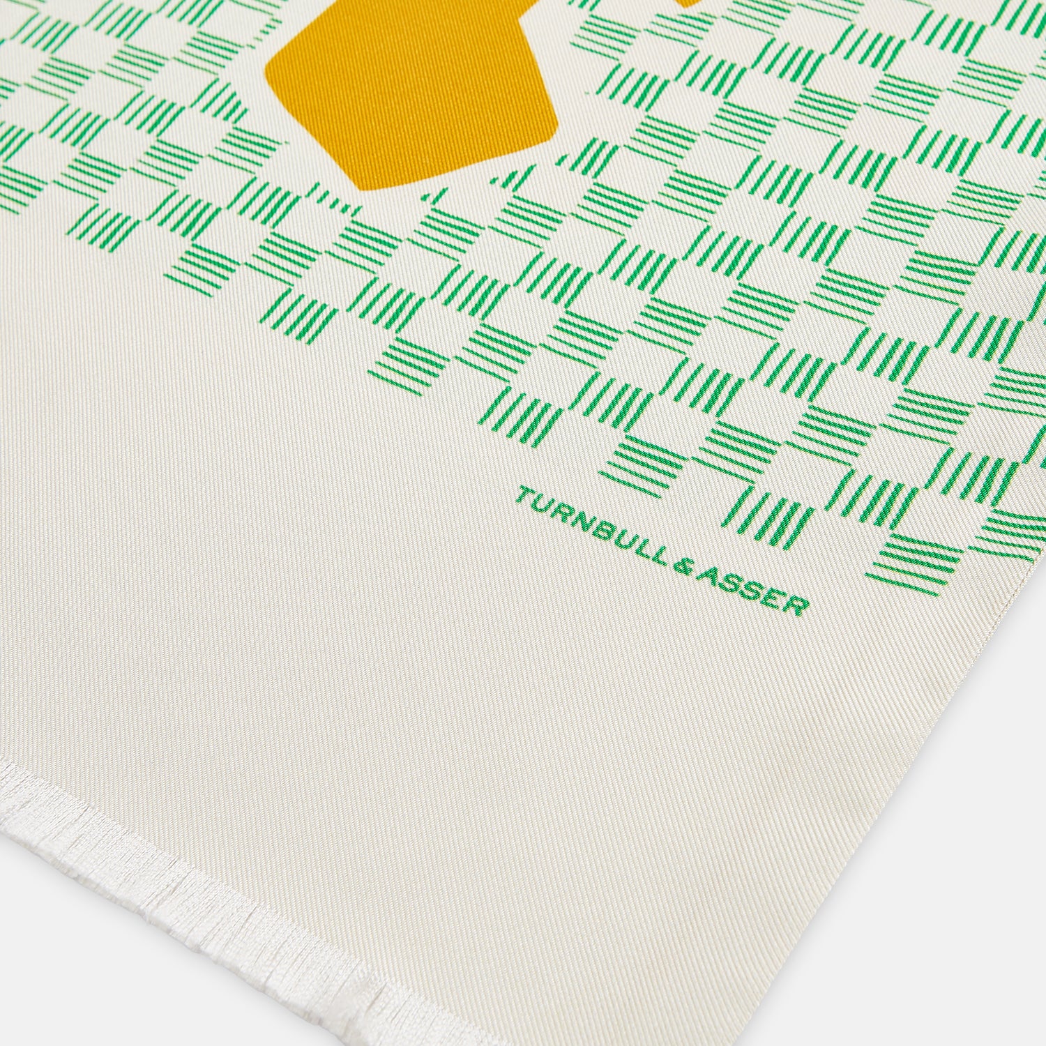 View 2 of product The Gold and Green Abstract Bird Silk Lawton Scarf by Turnbull & Asser features a white base with green checks, bold yellow Cubism-inspired bird motifs, and fringed edges, elegantly draped against a white background.