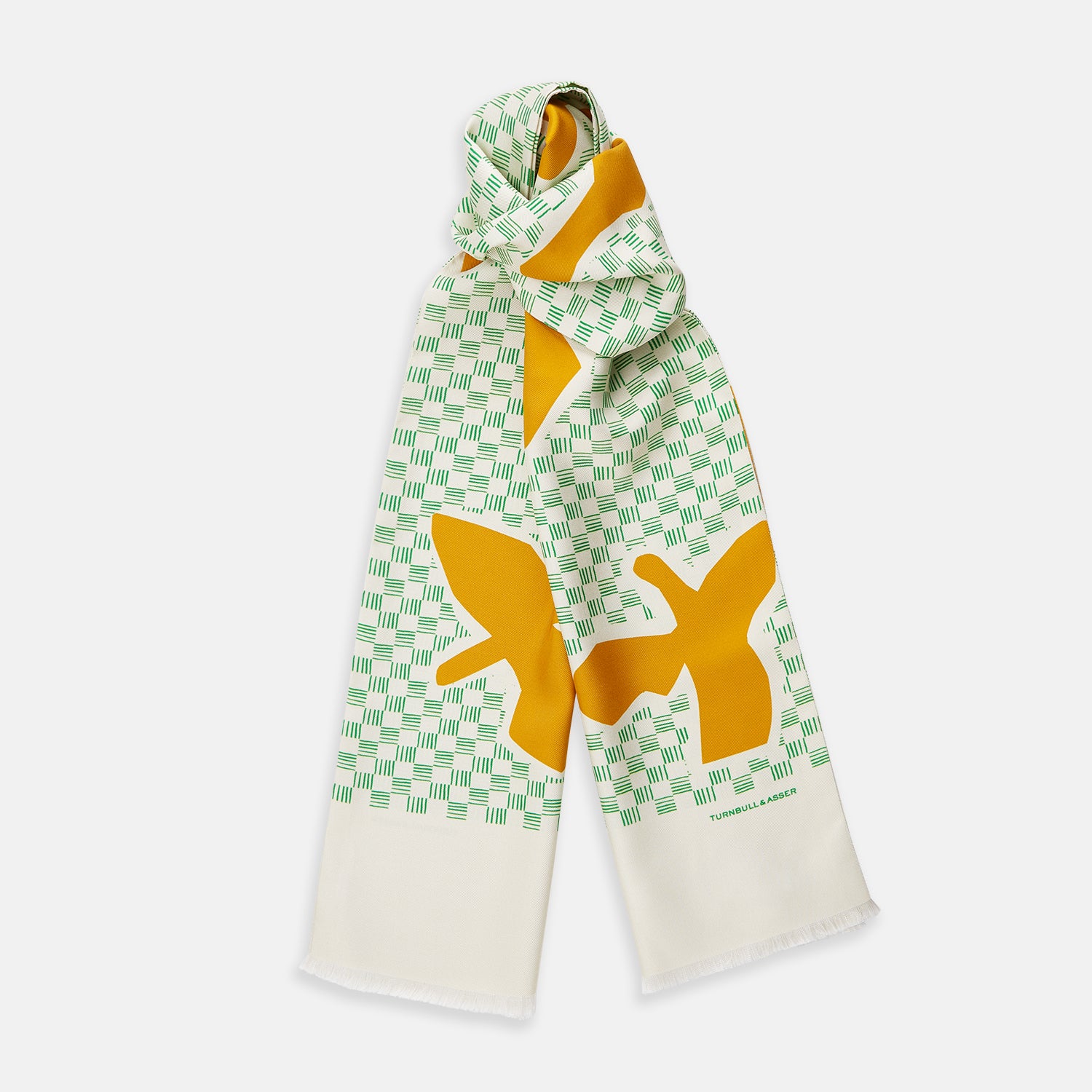 View 1 of product The Gold and Green Abstract Bird Silk Lawton Scarf by Turnbull & Asser features a white base with green checks, bold yellow Cubism-inspired bird motifs, and fringed edges, elegantly draped against a white background.