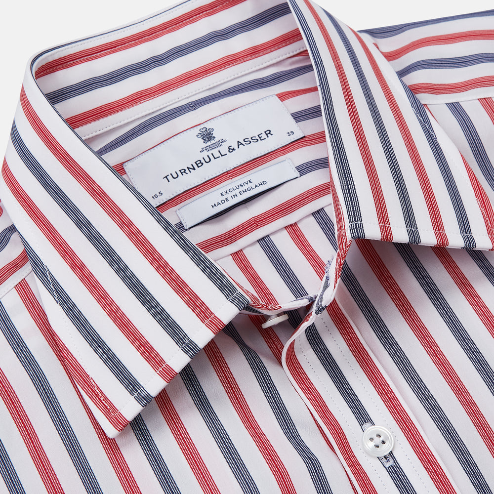 The Turnbull & Asser Red and Blue Stripe Cotton Regular Fit Whitby Shirt is a long-sleeve button-up featuring vibrant red and blue stripes on white, with a collar and buttoned cuffs, shown on a plain white surface.