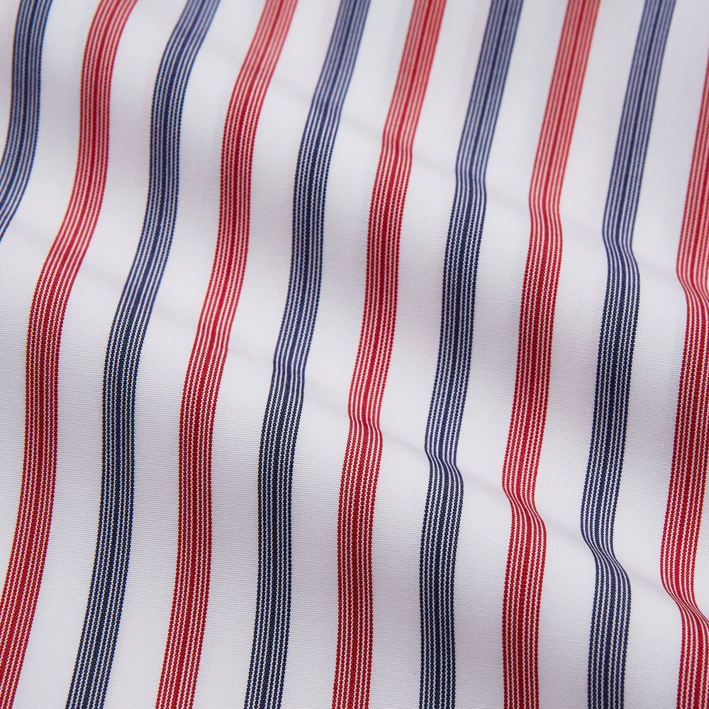 The Turnbull & Asser Red and Blue Stripe Cotton Regular Fit Whitby Shirt is a long-sleeve button-up featuring vibrant red and blue stripes on white, with a collar and buttoned cuffs, shown on a plain white surface.