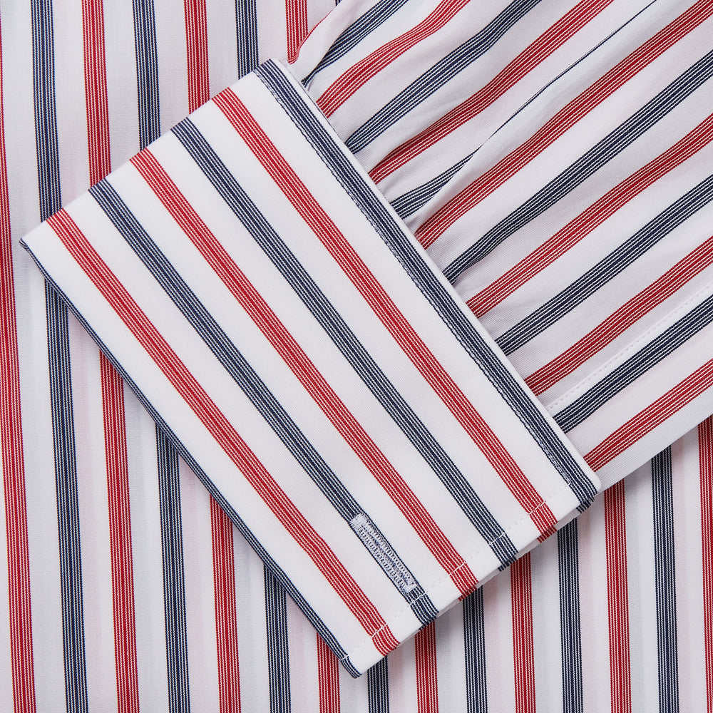 The Turnbull & Asser Red and Blue Stripe Cotton Regular Fit Whitby Shirt is a long-sleeve button-up featuring vibrant red and blue stripes on white, with a collar and buttoned cuffs, shown on a plain white surface.