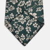 View 3 of product The Turnbull & Asser Dark Green Floral Garden Silk Tie features an elegant white floral pattern on dark green silk, shown rolled against a plain white background.