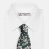 View 4 of product The Turnbull & Asser Dark Green Floral Garden Silk Tie features an elegant white floral pattern on dark green silk, shown rolled against a plain white background.