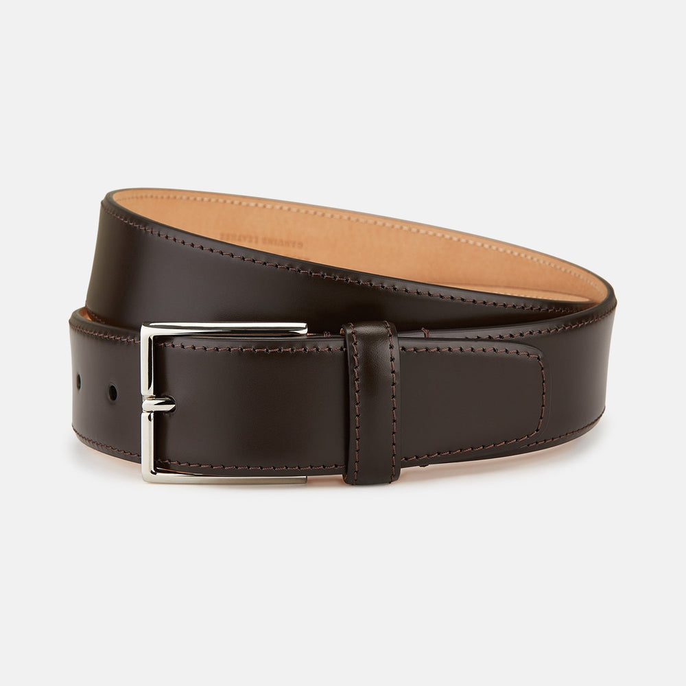 The Turnbull & Asser Dark Brown Nubuck Leather Evening Belt, featuring a silver rectangular buckle, is coiled neatly on a white background.