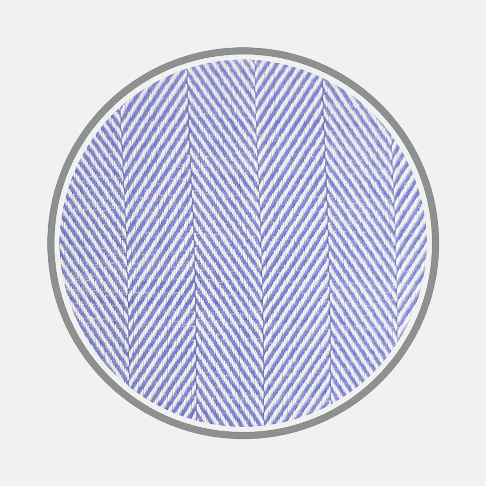 Close-up of BESPOKE FABRIC 0010 06 by Turnbull & Asser: a light blue and white herringbone pattern shown in a circular frame, ideal for custom shirts or distinctive monogram styles. Displayed against a plain white background.