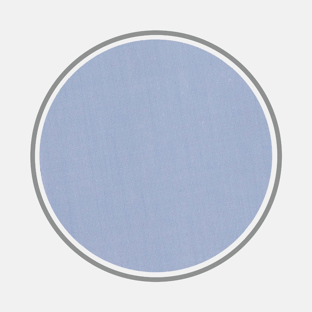 A circular swatch of BESPOKE FABRIC 0024 07 by Turnbull & Asser in light blue with a soft texture, framed by a gray ring, suggests refined quality for custom shirts on a white background.
