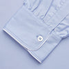 View 4 of product The Turnbull & Asser Blue Piped Sea Island Quality Cotton Nightshirt features light blue sea island cotton, a collared neckline with white piping, a front pocket, partial button placket, and a curved high-low hem for classic nightshirt style.