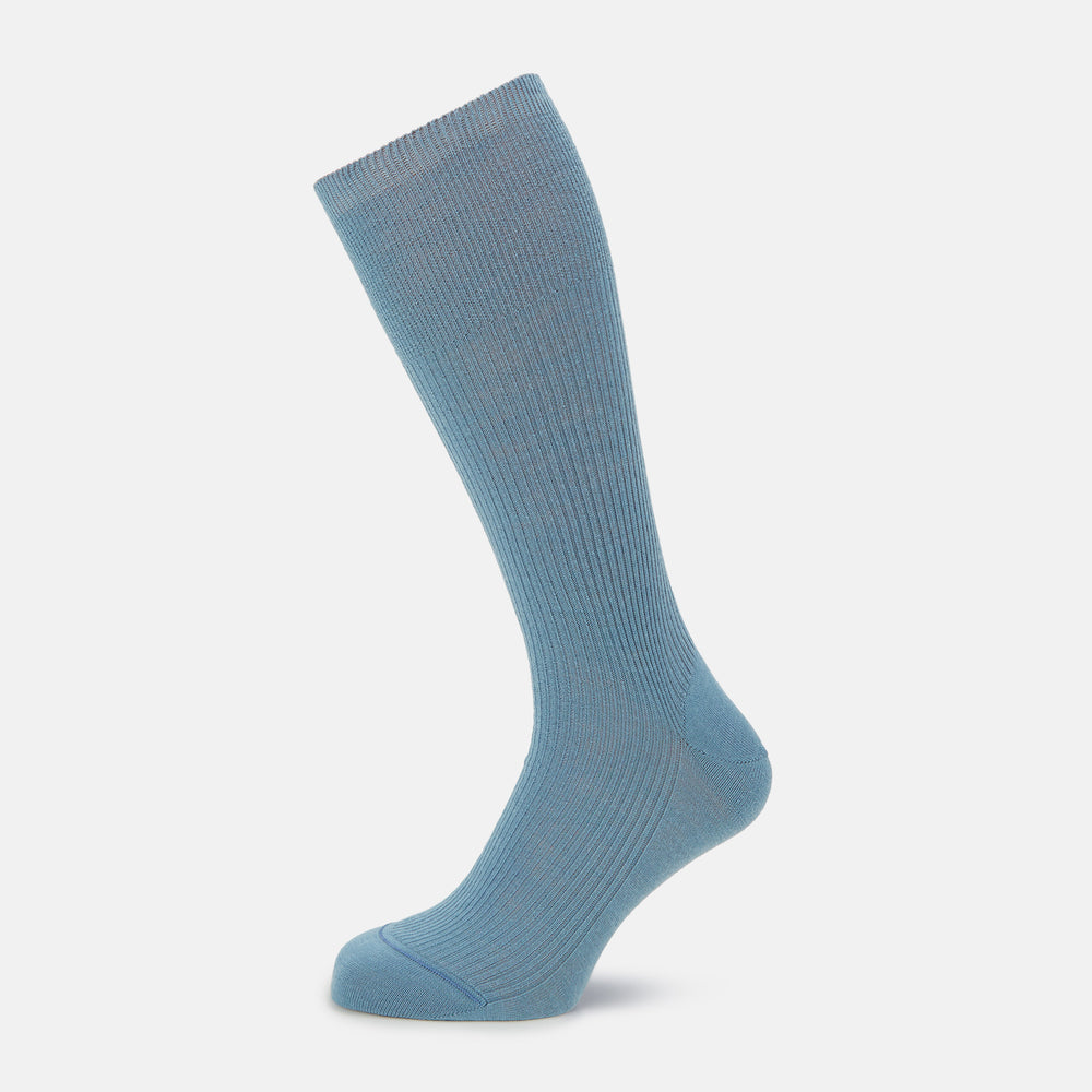 A single Pale Blue Mid-Length Merino Sock by Turnbull & Asser stands upright against a white background, highlighting its ribbed texture and reinforced toe and heel—showcasing the elegance of luxury merino wool.