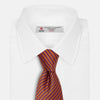 View 2 of product The Turnbull & Asser Die Another Day Stripe Silk Tie, as seen on James Bond, showcases a vibrant orange, red, and purple woven pattern, elegantly rolled and displayed against a white background.
