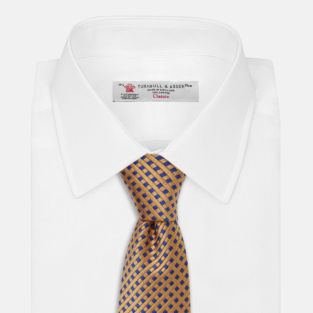 The Turnbull & Asser Tomorrow Never Dies Diamond Silk Tie, as seen on James Bond, features a gold and navy checkered pattern—an ideal gift for any Bond fan. Displayed rolled against a plain white background.