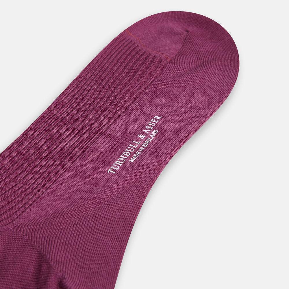 A single Turnbull & Asser Mauve Mid-Length Merino Sock is shown upright, foot angled downward, against a plain light gray background. The ribbed sock features a solid mauve color.
