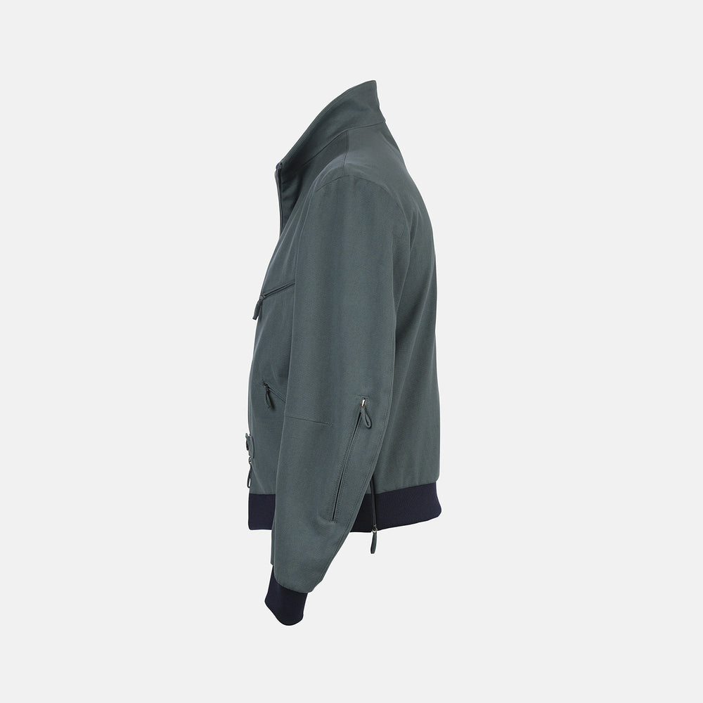 A Fairway Ash Grey Driving Jacket in Cotton by Turnbull & Asser UK, featuring a zip-up front, high collar, chest and side zip pockets, and dark ribbed cuffs and waistband; crafted from lightweight cotton for comfort and style, displayed on a plain white background.