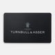 A sleek black Turnbull & Asser E-Voucher card displays the brand name in white, a small emblem above it, and the words "By Appointment to H.R.H. The Prince of Wales Shirtmakers" beneath the emblem.