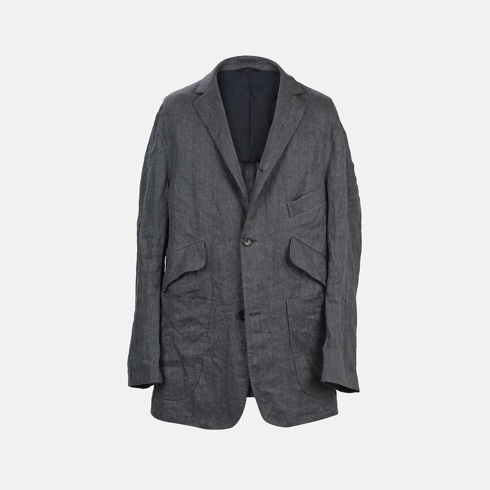 The Riviera Ash Oversized Blazer in Linen by Turnbull & Asser UK, showcased against a plain white background, features a single-breasted design in dark gray linen—ideal for summer tailoring—with two front buttons and large flap pockets. This jacket seamlessly combines classic style with breathable comfort.