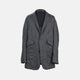 The Riviera Ash Oversized Blazer in Linen by Turnbull & Asser UK, showcased against a plain white background, features a single-breasted design in dark gray linen—ideal for summer tailoring—with two front buttons and large flap pockets. This jacket seamlessly combines classic style with breathable comfort.