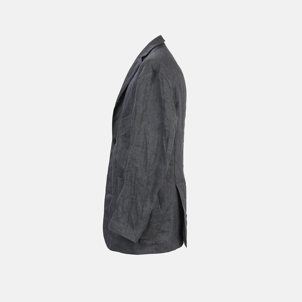 The Riviera Ash Oversized Blazer in Linen by Turnbull & Asser UK, showcased against a plain white background, features a single-breasted design in dark gray linen—ideal for summer tailoring—with two front buttons and large flap pockets. This jacket seamlessly combines classic style with breathable comfort.
