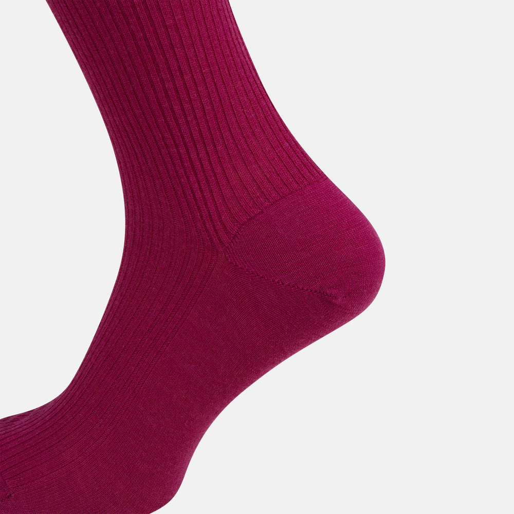 The Turnbull & Asser Magenta Mid-Length Merino Sock, featuring a ribbed design and crafted from soft merino wool, is displayed in a solid deep magenta color against a white background.