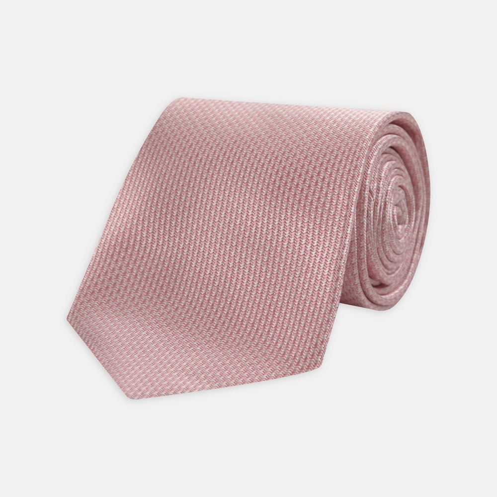 The Turnbull & Asser Pink Houndstooth Silk Tie, featuring a subtle textured pattern, is rolled up and displayed on a plain white background—ideal for pairing with your favorite office shirt.