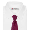 View 2 of product The Turnbull & Asser Dark Pink and Blue Spot Lace Silk Tie features small, evenly spaced blue dots on dark pink silk, shown rolled up against a white background.