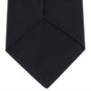 View 4 of product A neatly rolled Turnbull & Asser Navy Grenadine Silk Tie with a textured, knitted appearance is displayed on a white background.