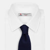 View 2 of product The Turnbull & Asser Slim Navy Herringbone Silk Tie is a refined men’s accessory, elegantly rolled and displayed on a plain white background.